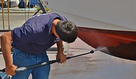 Man pressure washing underside of boat.