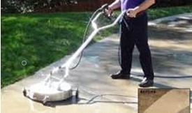 Man pressure washing concrete sidewalk with a surface cleaner.