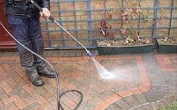 Man pressure washing paver patio.